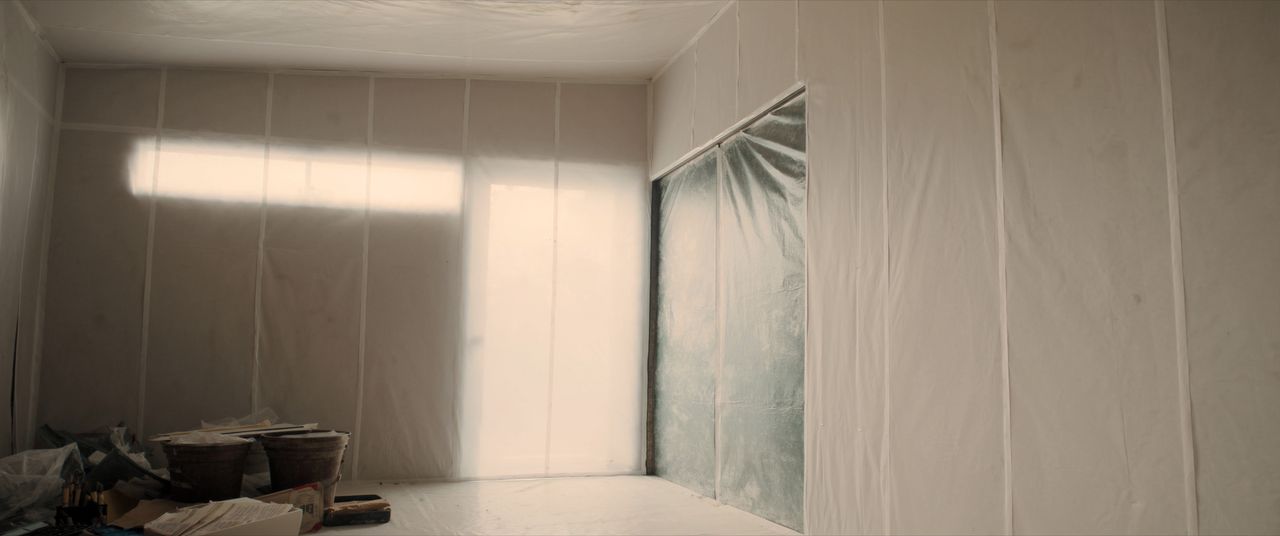 Room prepared with plastic containment sheeting for ceiling work